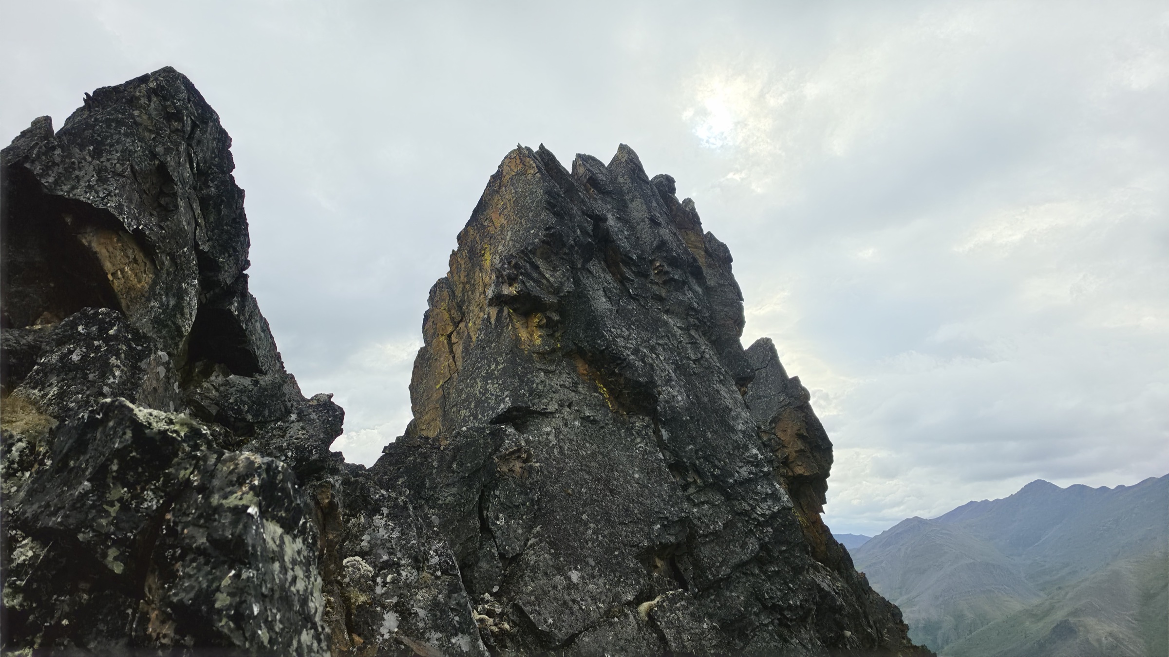 Sunlight breaking through cloud directly above a very dark shale pinnacle.